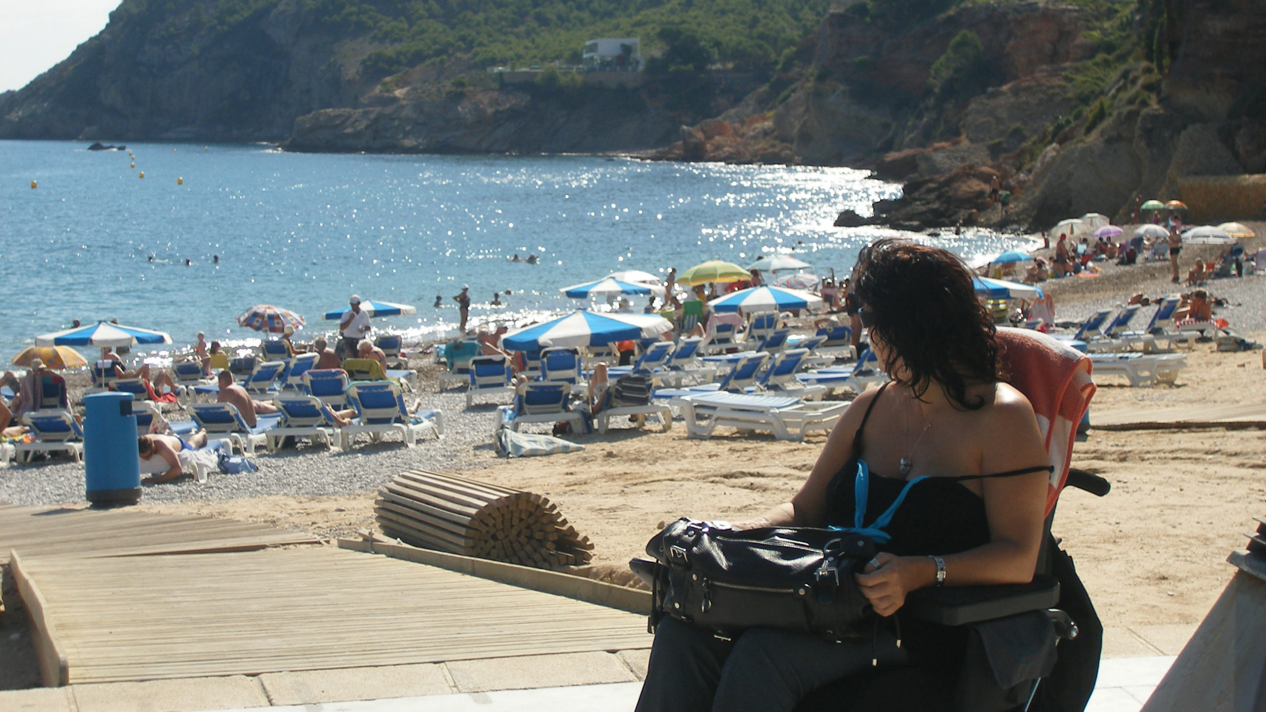 Mujer en silla de ruedas en la playa observando el mar